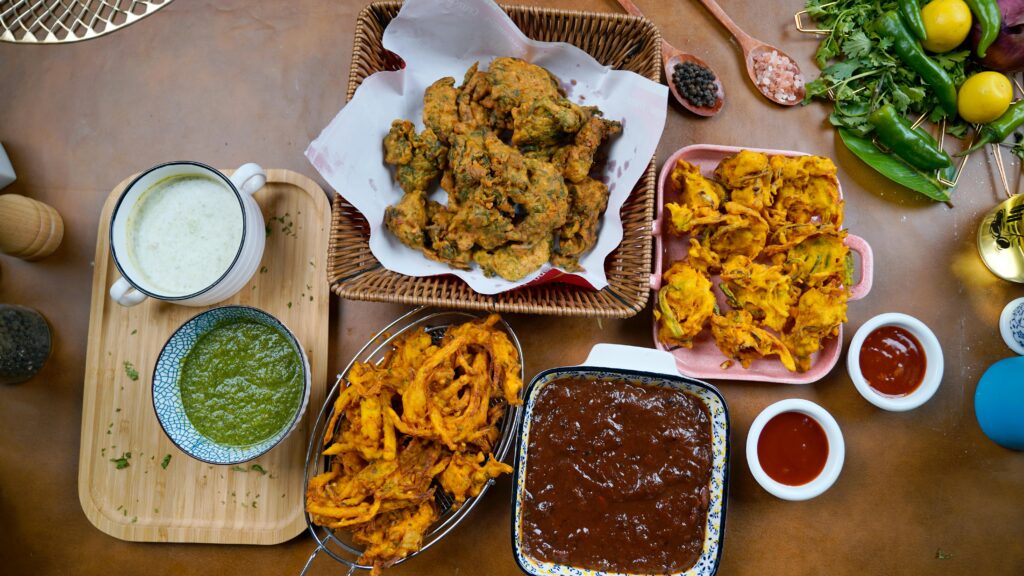 Top view of assorted Indian snacks with chutney dips on a table, showcasing vibrant flavors.